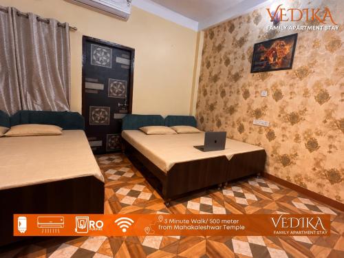 a room with two beds and a laptop on a table at Vedika Yatri Grah - Entire Apartment in Ujjain