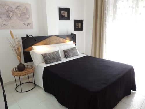 a bedroom with a black and white bed and a window at LOS NAREJOS Hotel in Los Alcázares