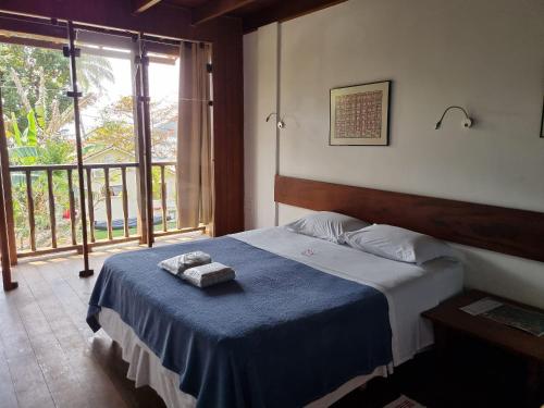 a bedroom with a bed with two towels on it at Pousada Manacá — Beachfront Guesthouse on Ilha Grande in Abraão