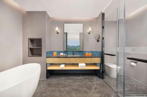a bathroom with a tub and a sink and a toilet at Four Points by Sheraton Leshan in Leshan