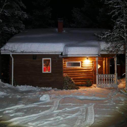 a log cabin with snow on the roof at night at Ditt andra hem in Kiruna