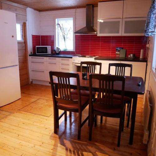 a kitchen with a table and chairs and red tile at Ditt andra hem in Kiruna