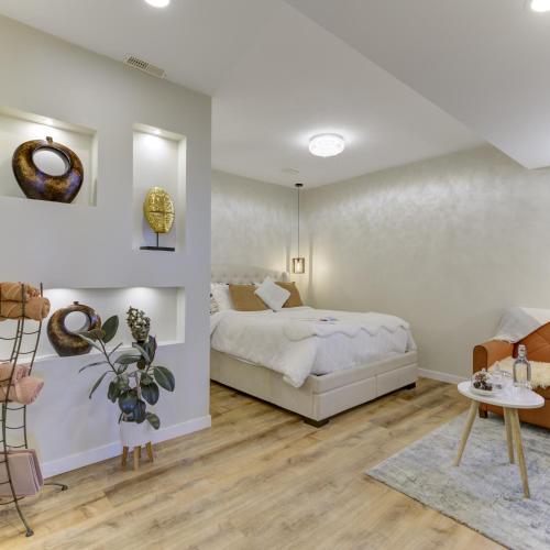 a white bedroom with a bed and a table at Unwind centrally in West Kelowna
