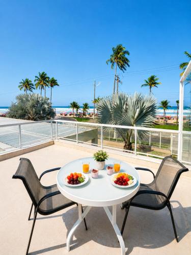 a table with two chairs and a table with food on it at Makai Hotel Boutique - Frente Mar in Guarujá