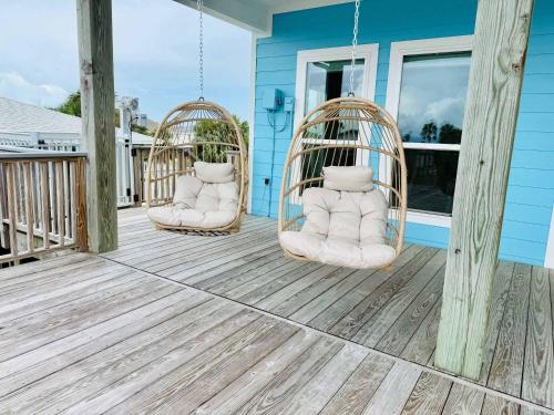 two swings on the front porch of a blue house at Dockside Dream Home for 10 in Galveston