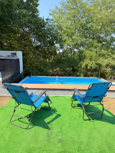two chairs sitting on the grass in front of a pool at ALBAK Green Zone in Gradačac