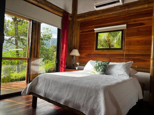 a bedroom with a bed and a large window at Bambura Hermosa villas in Uvita