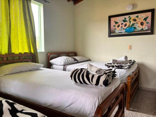 two beds in a room with zebra towels on them at Hotel Casa Verde Guatapé in Guatapé