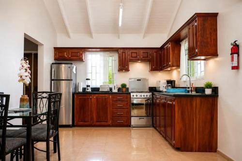 a kitchen with wooden cabinets and a stainless steel refrigerator at Piton Views & Sunset Balcony, Minutes to Beaches in Soufrière