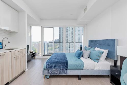 a bedroom with a bed and a large window at Executive Studio w Balcony Steps to Eaton Centre in Toronto