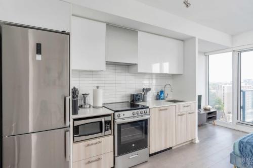 a kitchen with white appliances and a large window at Executive Studio w Balcony Steps to Eaton Centre in Toronto