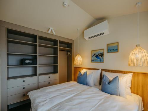 a bedroom with a large white bed with blue pillows at Guesthouse Naturgarten in Breitenbrunn