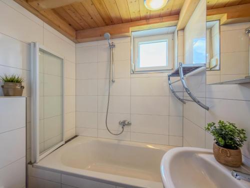 a bathroom with a tub and a window and a sink at Kipaji 3 in Kötschach