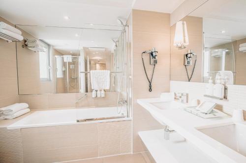 a white bathroom with two sinks and a shower at Holiday Inn Mulhouse by IHG in Mulhouse