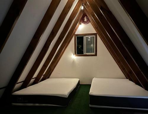 two beds in a attic with a window at Los boldos in Concón