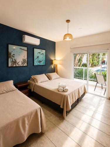 a bedroom with two beds and a large window at Makai Hotel Boutique - Frente Mar in Guarujá