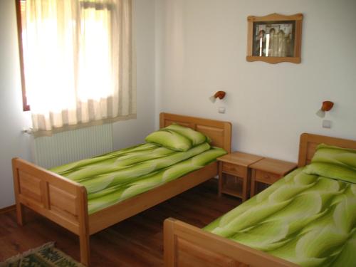 two beds in a room with green sheets and a window at Kúria Vendégház in Cristuru Secuiesc