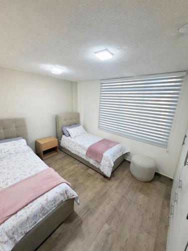 a bedroom with two beds and a window with blinds at Modern and cozy in Riobamba in Riobamba