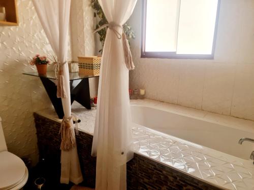 a bathroom with a tub and a window and a toilet at Arins House in Cusco