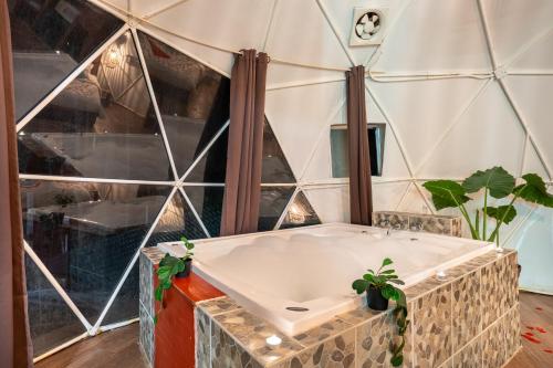 a bath tub in a room with a glass wall at Glamping-Zingo in Santa Ana Jilotzingo