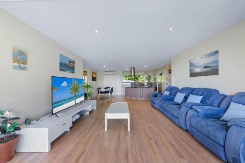 a living room with a blue couch and a tv at Getaway Ocean Views KIDS STAY FREE in Airlie Beach