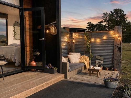 a patio with a couch on a deck with lights at Field and Fleece Farm Stay by Tiny Away in Claremont