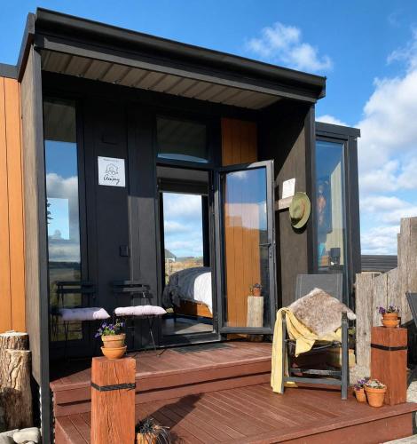a black tiny house with a bed on a deck at Field and Fleece Farm Stay by Tiny Away in Claremont