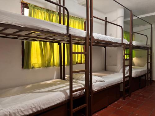 two bunk beds in a room with yellow curtains at Hostal Casa Lulú Santa Marta in Santa Marta