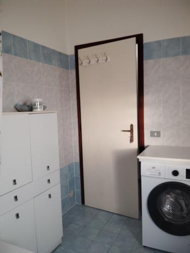 a bathroom with a washing machine and a white door at Room Bed Garden in Berra