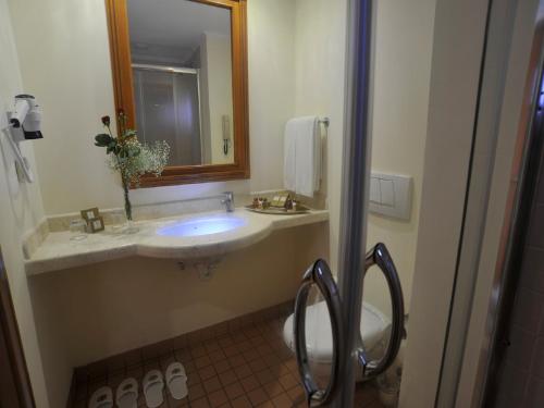 a bathroom with a sink and a mirror and a toilet at Akka Claros Hotel - All Inclusive in Kemer