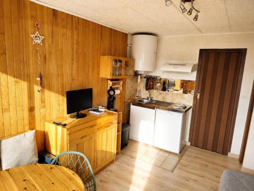 a kitchen with wooden walls and a table and a refrigerator at L'HappyMijoux in Mijoux