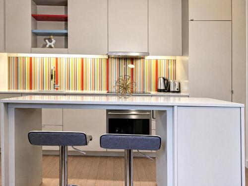 a kitchen with a white counter with two stools at The C Park Hotel and Suites in Toronto
