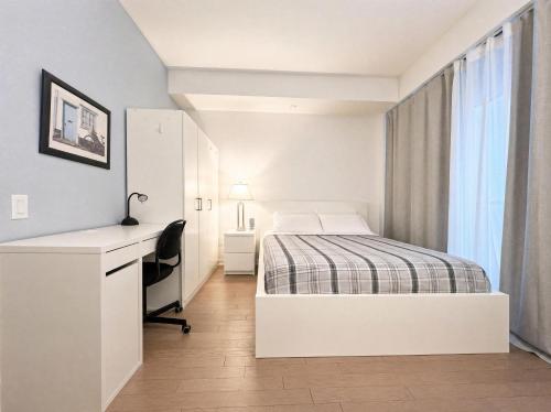 a white bedroom with a bed and a desk at The C Park Hotel and Suites in Toronto