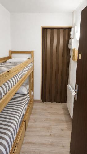 two bunk beds in a room with a wooden door at L'HappyMijoux in Mijoux