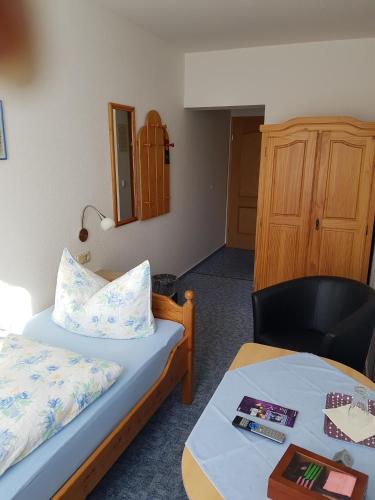 a room with two beds and a table and a chair at Pension Schweizer Hof in Wernigerode