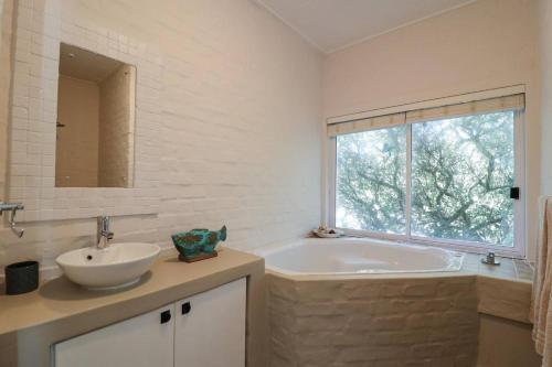 a bathroom with a tub and a sink and a window at Vinho Verde Splendid Sea View Jacuzzi in Franskraalstrand