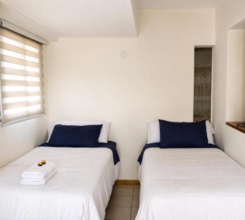 two beds with blue and white sheets in a room at Dorrego Apart 3 in Guaymallen