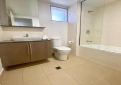 a bathroom with a toilet and a sink and a shower at Nature Meets City on Mint in Townsville