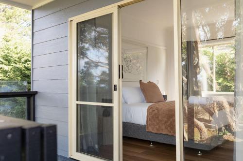 a bedroom with a bed and a sliding glass door at Hamptons on the Bay in Swansea