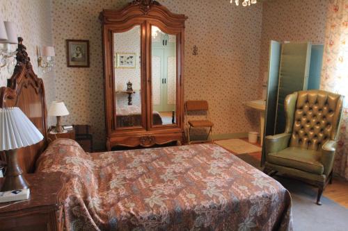 a bedroom with a bed and a chair and a mirror at La Panoramique des Puys in Vollore-Ville