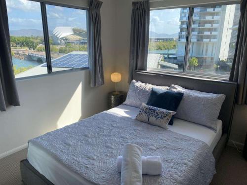 a bedroom with a bed with pillows and windows at Tranquil 3 Bedroom Retreat in Townsville City in Townsville