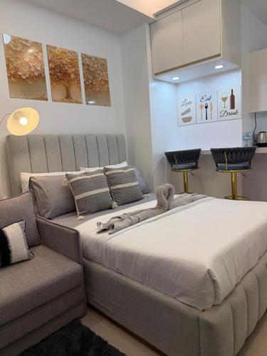 a bedroom with a large bed and a couch at Azzure North Pampanga Cloudline Suite 418 Barbados in San Fernando