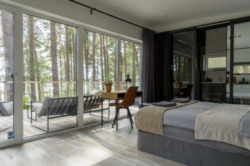 a bedroom with a bed and a table and a balcony at Gauja Lakeside in Gauja