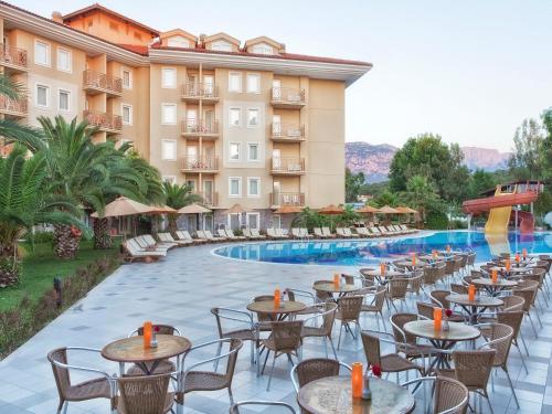 um hotel com mesas e cadeiras ao lado de uma piscina em Akka Claros Hotel - All Inclusive em Kemer