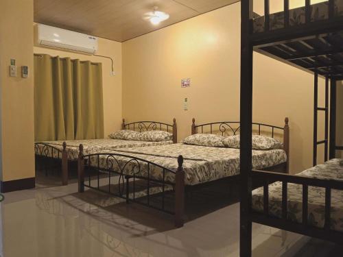 a room with three bunk beds in a room at Bahay Domingo Guesthouse & Private Pool in Bagac