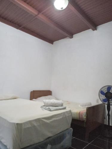 a bedroom with two beds and a table with a fan at Hostel Casa María in Masaya