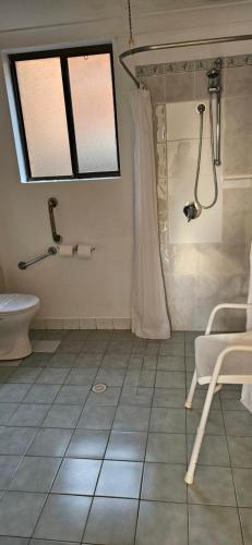 a bathroom with a shower and a toilet and a window at Port O'Call Motel in Port Macquarie