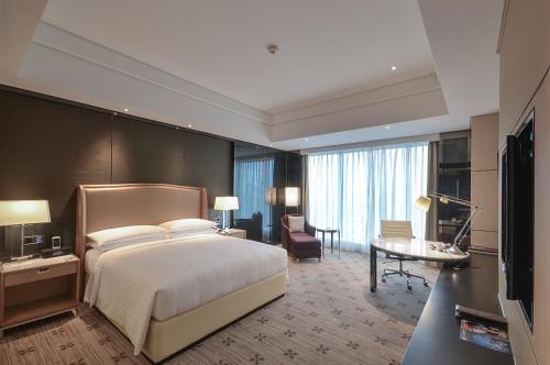 a hotel room with a large bed and a desk at Zhuzhou Marriott Hotel in Zhuzhou