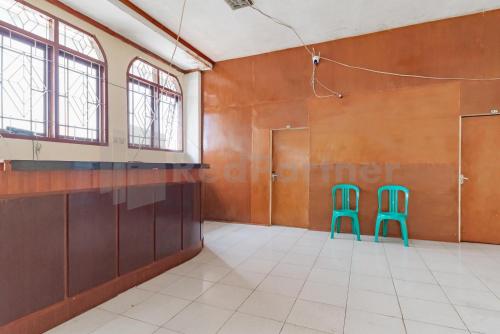 two green chairs in an empty room with windows at Bojongsoang Guesthouse RedPartner in Bandung