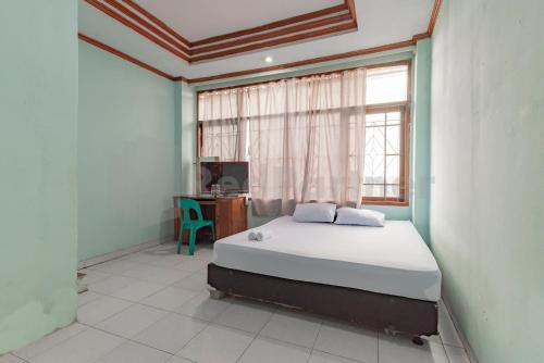 a bedroom with a bed and a window and a desk at Bojongsoang Guesthouse RedPartner in Bandung